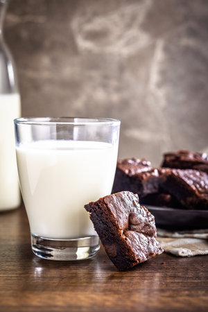 Homemade chocolate brownies and glass of milk on a wooden table.の写真素材