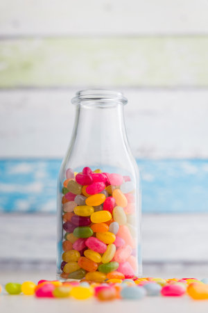 Multicolored jelly beans with various flavors in a jar on a kitchen table.の写真素材