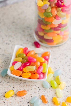 Multicolored jelly beans with various flavors in a bowl on a kitchen table.の写真素材