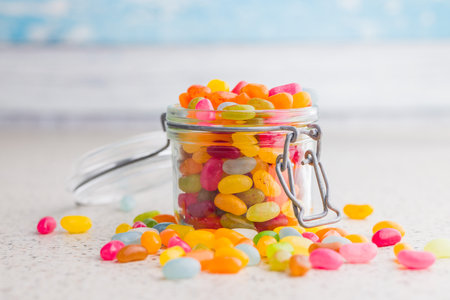Multicolored jelly beans with various flavors in a jar on a kitchen table.の写真素材