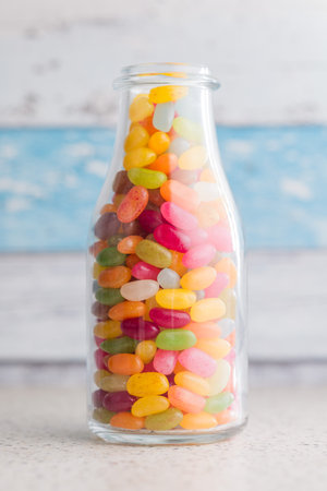 Multicolored jelly beans with various flavors in a jar on a kitchen table.の写真素材