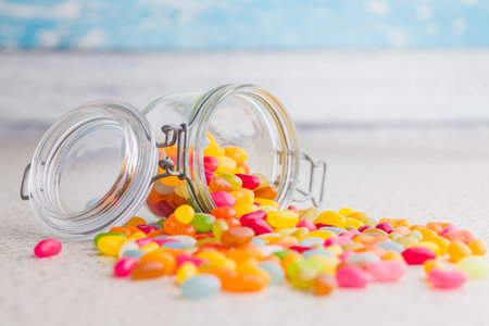 Multicolored jelly beans with various flavors in a jar on a kitchen table.の写真素材