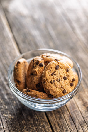 Chocolate chip cookies in a bowl on a wooden table.