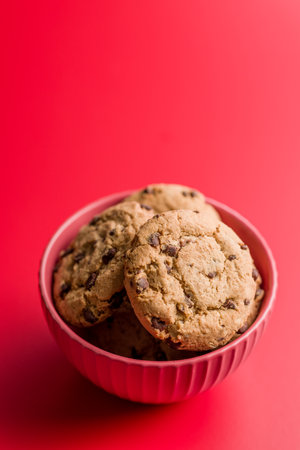 Chocolate chip cookies in a bowl on a red background.の写真素材