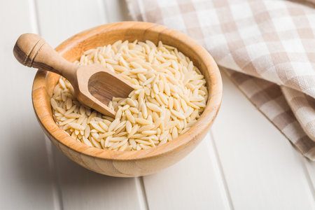 Orzo, kritharaki, risoni pasta. Uncooked dry pasta in a bowl on a white table.の写真素材
