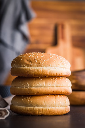 Empty burger bun with sesame seeds on a black table.の写真素材