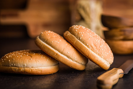 Empty burger bun with sesame seeds on a black table.の写真素材