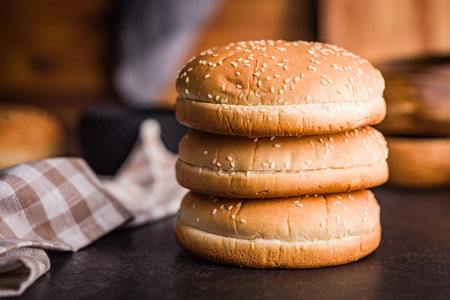 Empty burger bun with sesame seeds on a black table.
