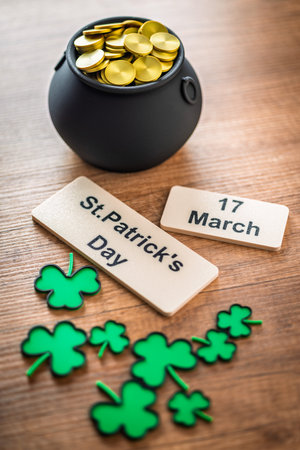 St. Patrick's Day. Green clover leaves decoration and cauldron with golden coins on a wooden table.の写真素材