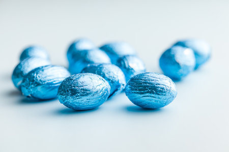 Chocolate easter eggs wrapped in blue colored foil on a blue background.の写真素材