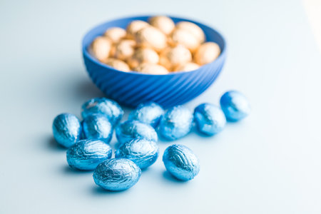 Chocolate easter eggs wrapped in blue colored foil on a blue background.の写真素材