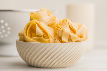 Italian pasta tagliatelle. Uncooked noodle pasta in a bowl on a kitchen table.の写真素材