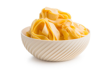 Italian pasta tagliatelle. Uncooked noodle pasta in a bowl isolated on a white background.の写真素材