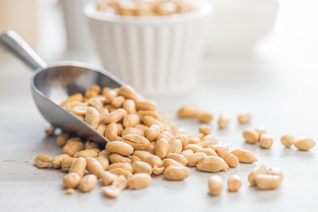 Roasted salted peanuts in a scoop on a kitchen table