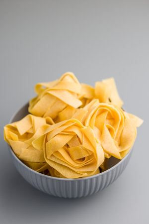 Italian pasta tagliatelle. Uncooked noodle pasta in a bowl on a gray background.の写真素材