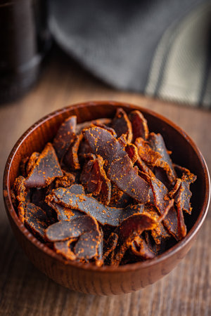 Beef jerky. Dried spiced meat in a bowl on a wooden table.の写真素材