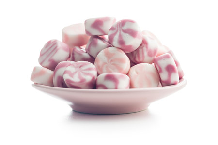 Colorful striped candies on a plate isolated on a white background.