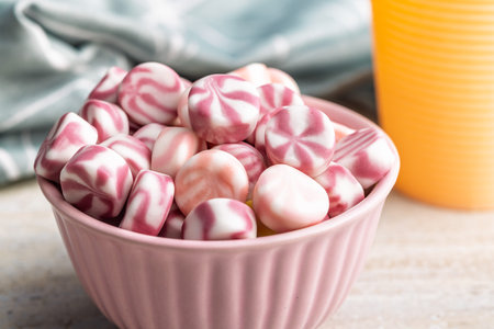 Colorful striped candies in a bowl on a kitchen table.の写真素材