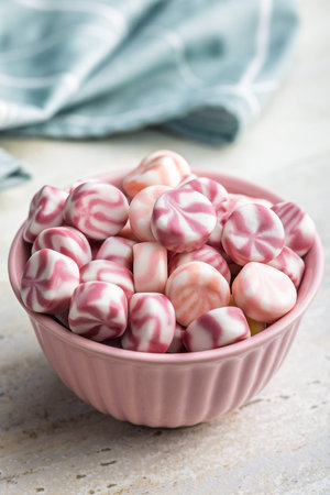 Colorful striped candies in a bowl on a kitchen table.の写真素材
