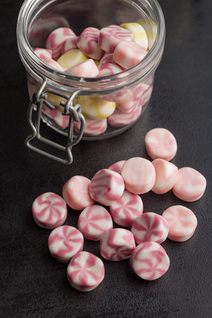 Colorful striped candies on a black table.の写真素材