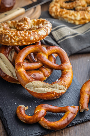 Salted bavarian pretzel on cutting board on a wooden table.