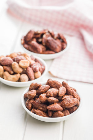Almond nuts coated in sugar and honey in a bowl on a white table.の写真素材