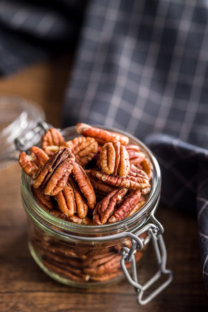 Peeled pecan nuts in jar on a wooden table.