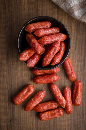 Mini salami sausages in a bowl on a wooden table. Top view.の写真素材