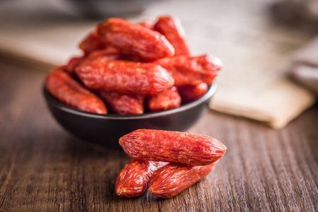Mini salami sausages in a bowl on a wooden table.の写真素材