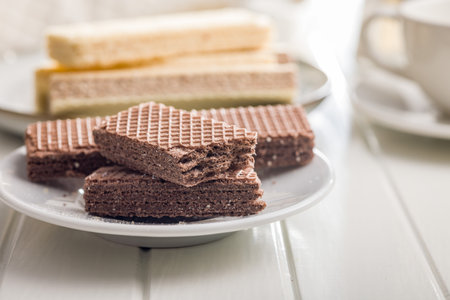 Sweet wafers filled with chocolate cream on a plate on a white table.の写真素材