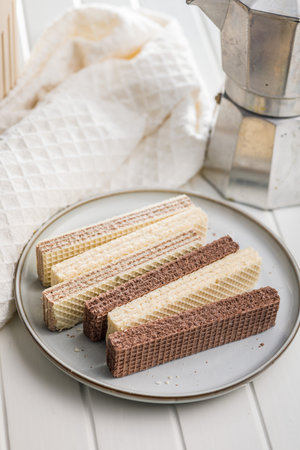 Sweet wafers filled with chocolate and vanilla cream on a plate on a white table.の写真素材