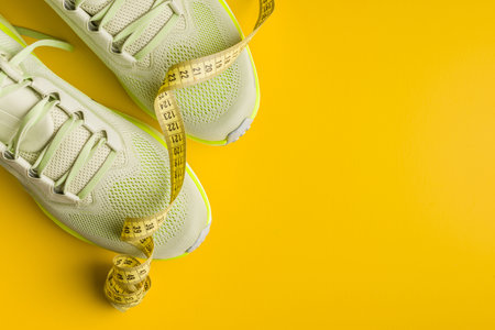 Sport running shoes and measuring tape on the yellow background. Top view.の写真素材