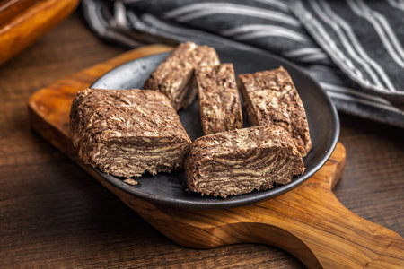 Halva with cocoa. Sweet oriental dessert on a plate on a wooden table.