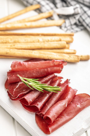 Slices of smoked bresaola on a white table.