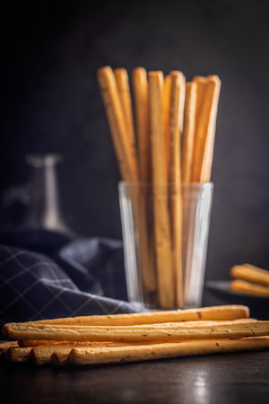Crispy grissini breadsticks on a black table.
