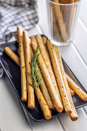 Crispy grissini breadsticks on a plate on a table.