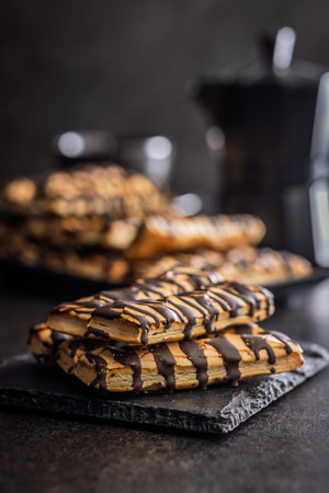 Sfogliatine glazed with chocolate. Italian crispy dessert on a black table.の写真素材
