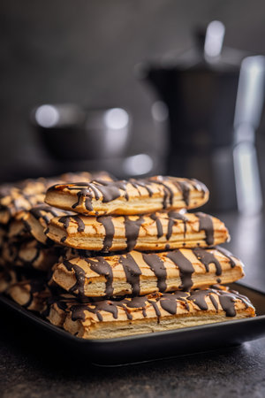 Sfogliatine glazed with chocolate. Italian crispy dessert on a plate on a black table.の写真素材