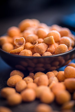 Peanuts in a crispy crust on a black table.の写真素材