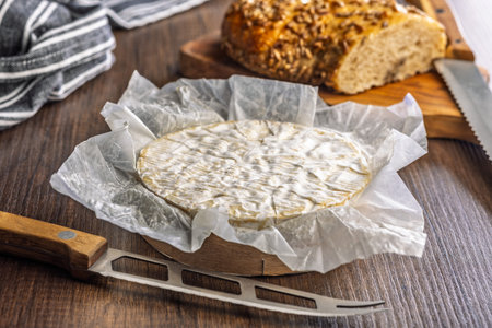 Camembert cheese on a wrapping paper. French cheese with mold on the surface.