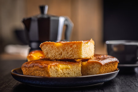 Catalana sponge cake on plate on a black table.