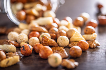 Salted snack. Coated peanuts and mini crackers on a wooden table.