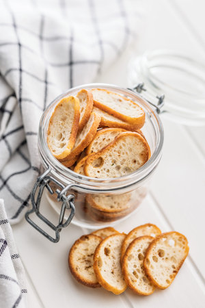 Crispy roasted bruschetta bread in a jar on a white table.の写真素材