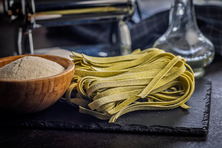 Green tagliatelle pasta on a black table.の写真素材