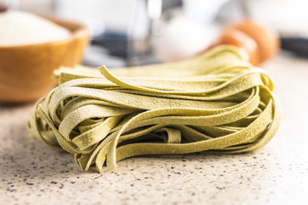 Green tagliatelle pasta on a kitchen table.の写真素材