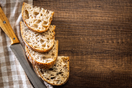 Photo of sliced â€‹â€‹â€‹â€‹baked sourdough bread on a wooden table. Top view.