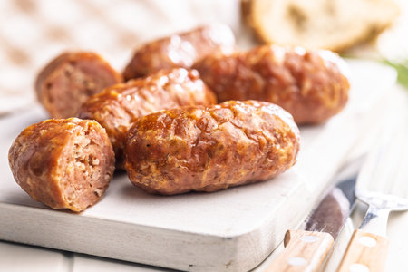 Photo of roasted Italian sausage salsiccia on a cutting board on a white table.の写真素材