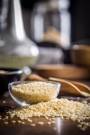 Roasted sesame seeds in a bowl on a wooden table.の写真素材