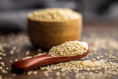 Roasted sesame seeds on a spoon on a wooden table.