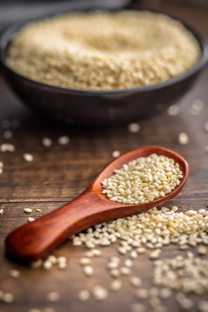 Roasted sesame seeds on a spoon on a wooden table.の写真素材